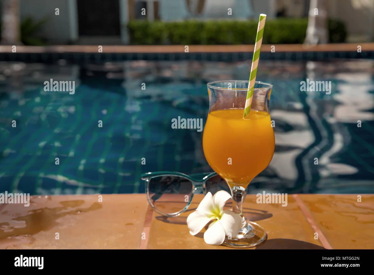 Succo di arancia con gli occhiali da sole sul al bordo della piscina - vacanza concetto tropicale Foto Stock