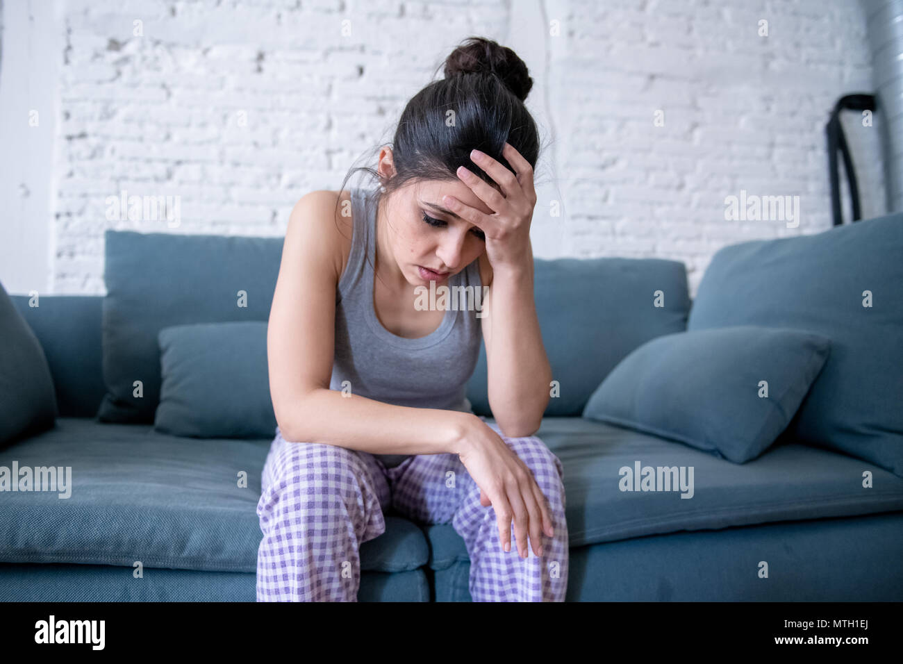 Bellissimo il latino premuto lonely donna a guardare fuori sensazione triste, dolore, dolore a casa sua e divano. Crisi, depressione e salute mentale concetto Foto Stock