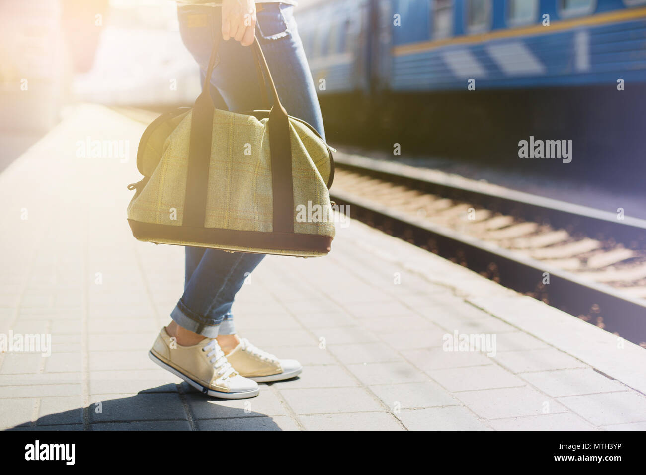 Donna che mantiene un sacchetto in corrispondenza di una stazione ferroviaria. In attesa dei passeggeri in treno. Foto Stock