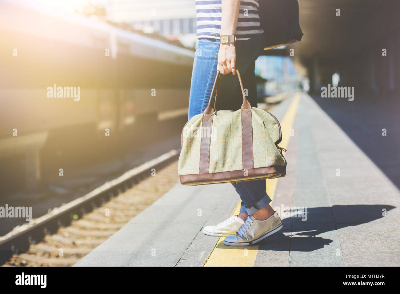 La donna in attesa del treno e tenendo un sacco ad una stazione ferroviaria. Traveler. Foto Stock
