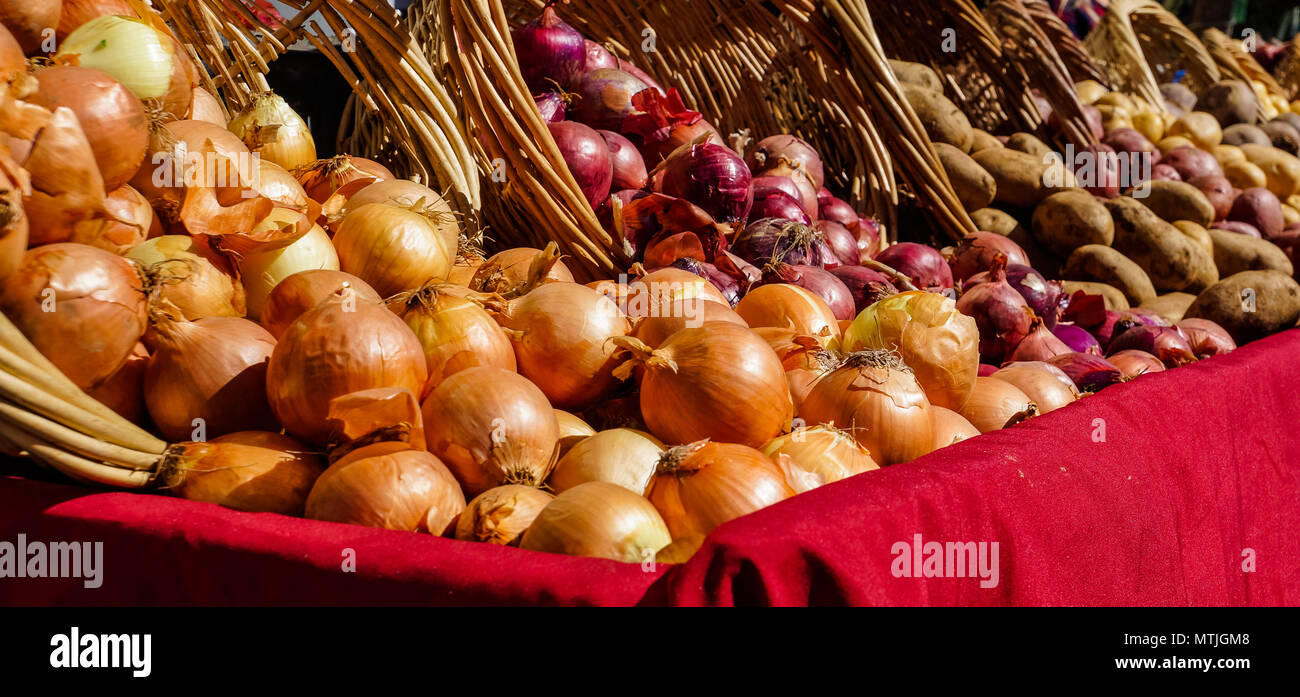 Le cipolle e le patate la fuoriuscita dei cesti sulla tabella per la vendita al mercato degli agricoltori Foto Stock