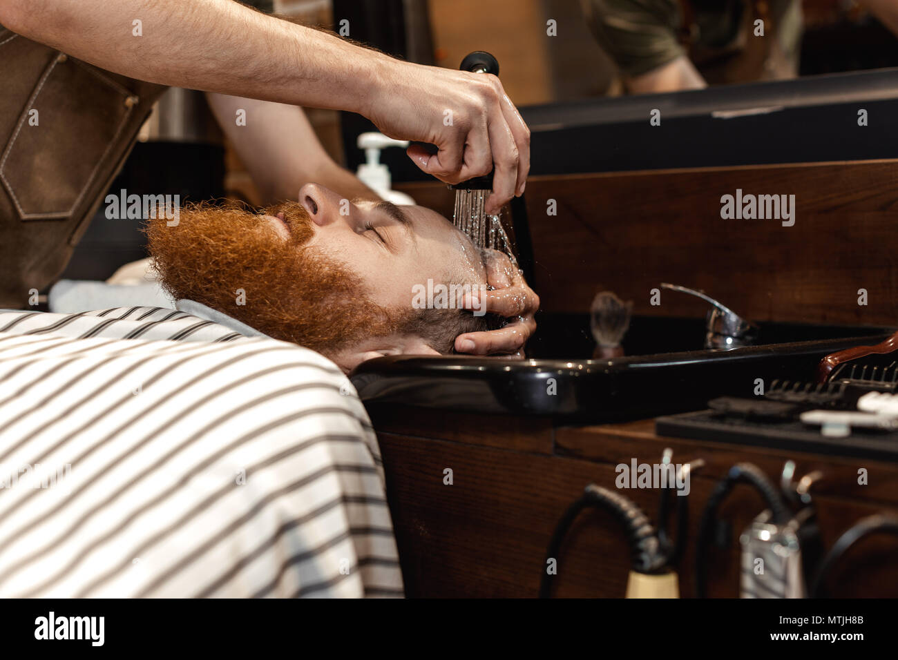 Barbiere e uomo barbuto in un barbiere Foto Stock
