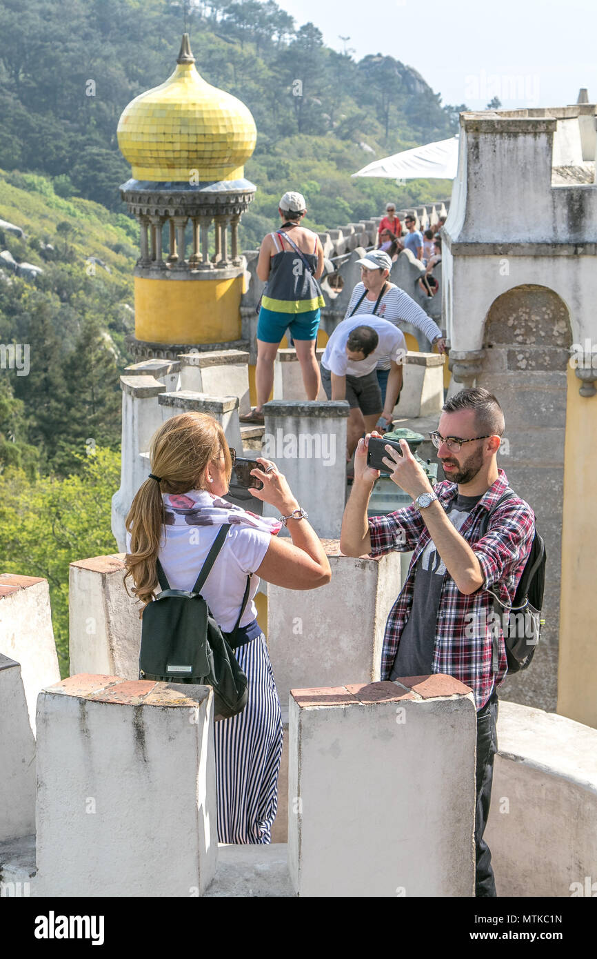 L uomo e la donna sono a scattare foto di Pena Palace utilizzando i propri smartphone. Sintra, Portogallo. Foto Stock