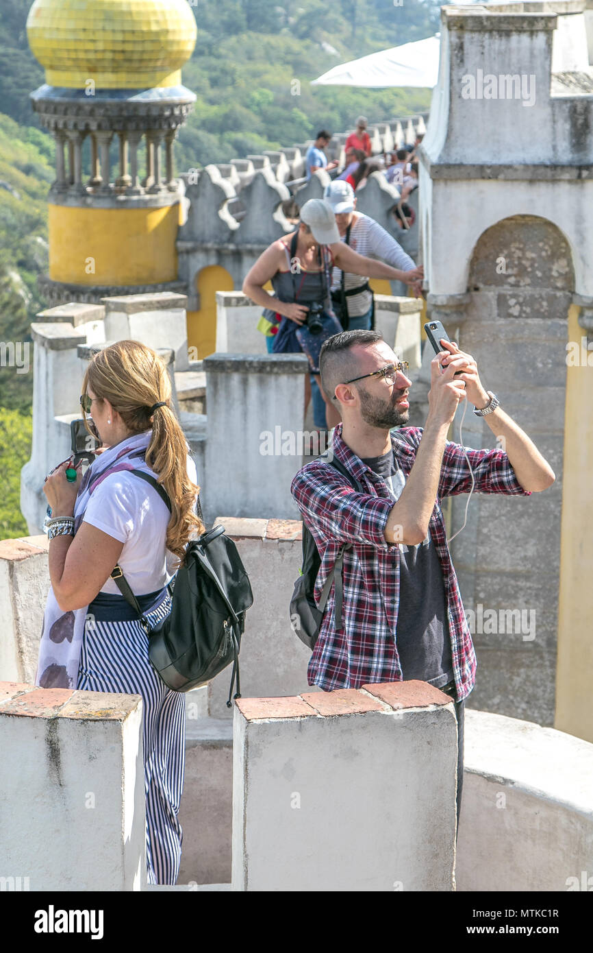L uomo e la donna sono a scattare foto di Pena Palace utilizzando i propri smartphone. Sintra, Portogallo. Foto Stock