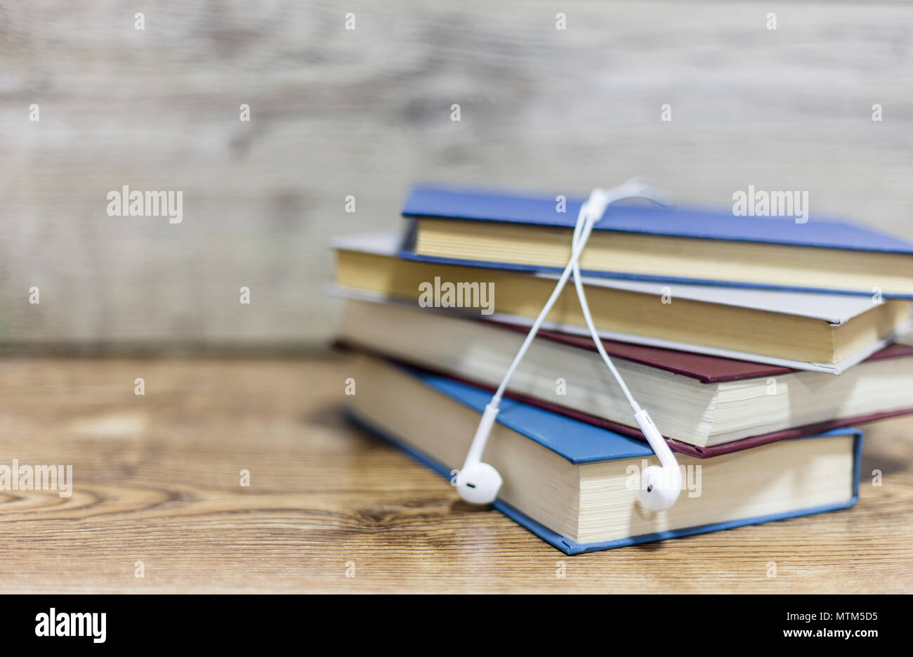 Sfocato quattro libri e auricolare su un tavolo di legno Foto Stock