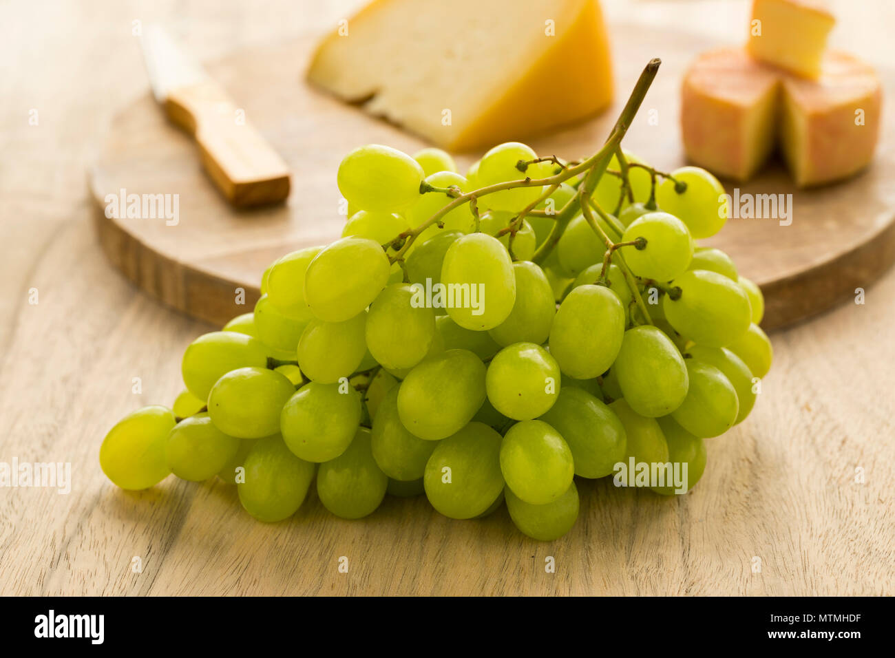 Fresca uva verde con sullo sfondo il formaggio su una tavola di legno Foto Stock