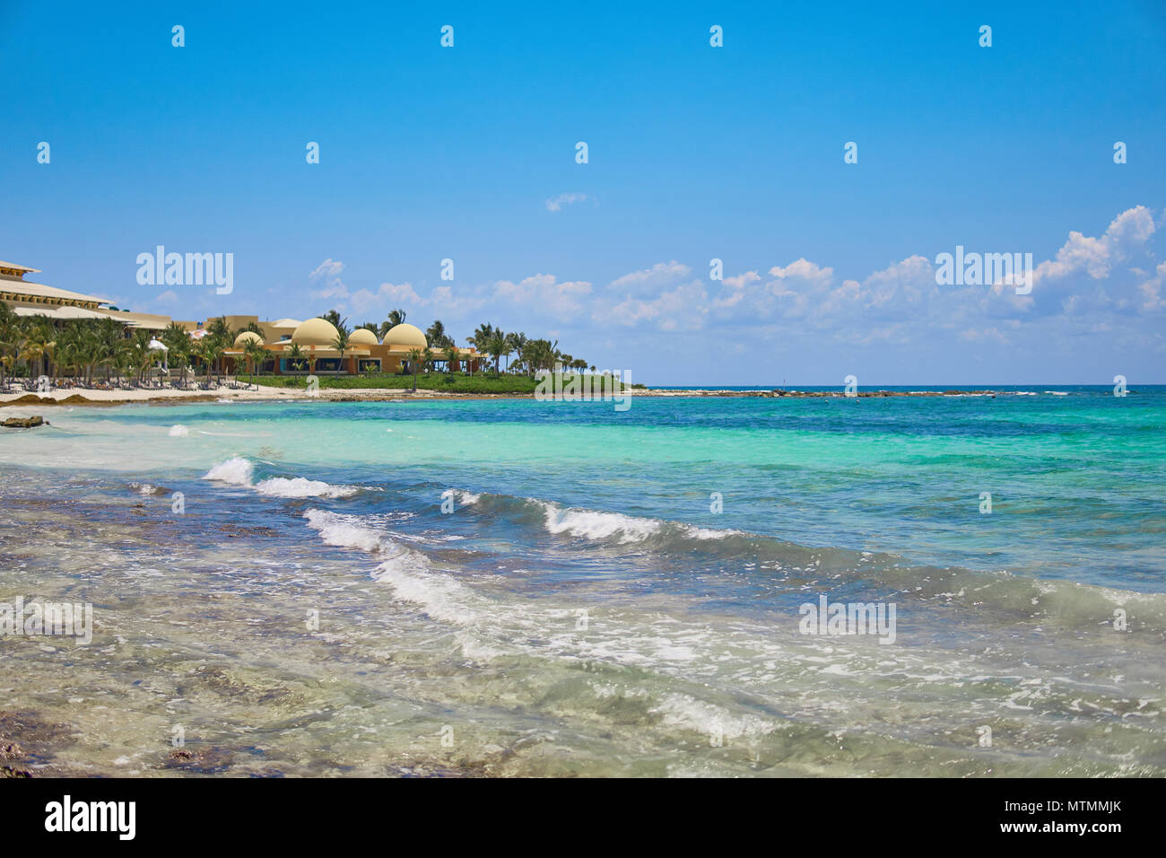 Vista resort hotel di lusso di spiaggia di Costa Tropicale. Foglie di palme da cocco che fluttua nel vento contro il cielo blu. Acque turchesi del Mar dei Caraibi. Riviera Maya Messico. Foto Stock