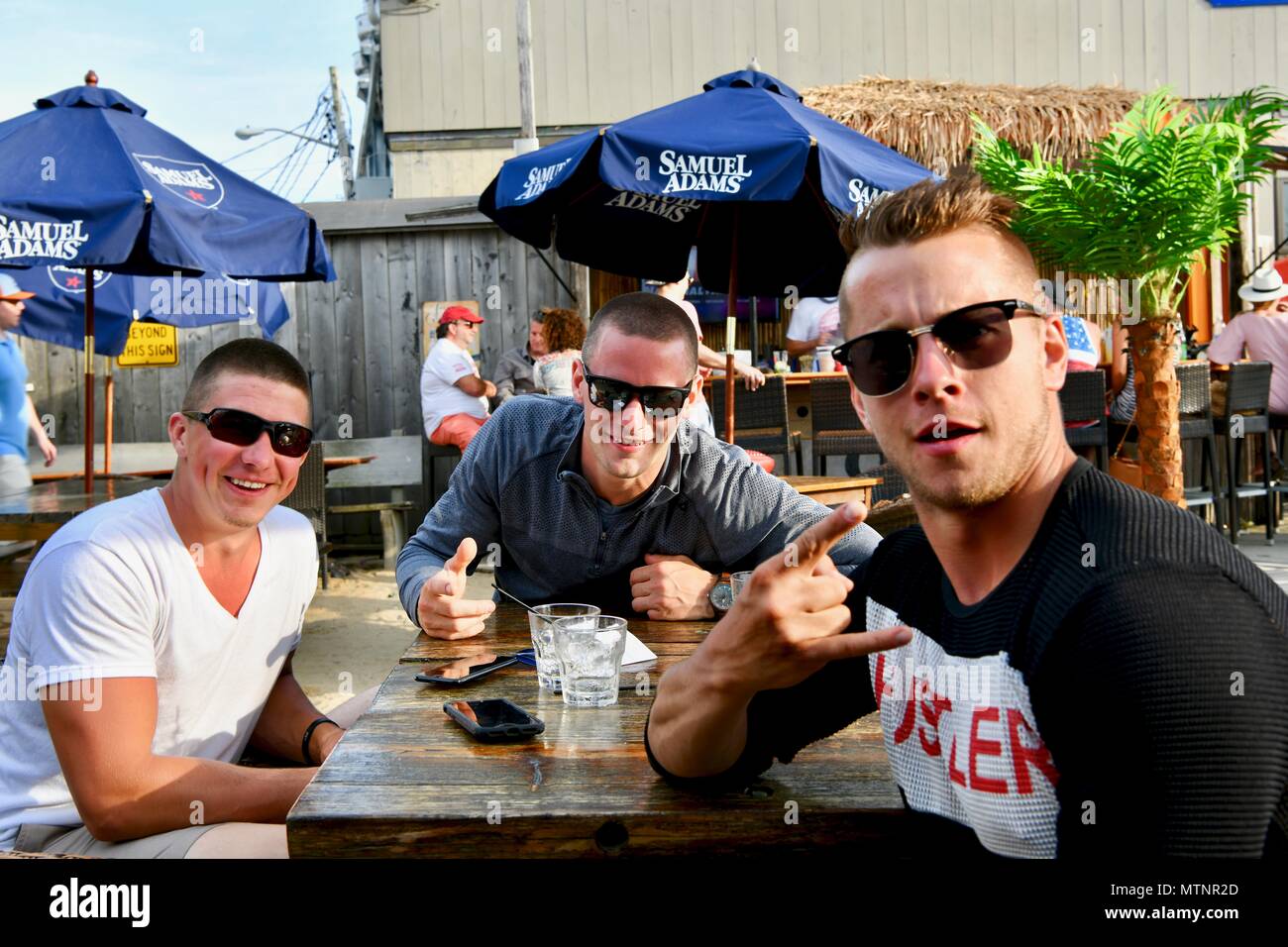 Tre uomini di età compresa tra i 21-30 avente alcune birre in un ristorante con sala da pranzo esterna Foto Stock