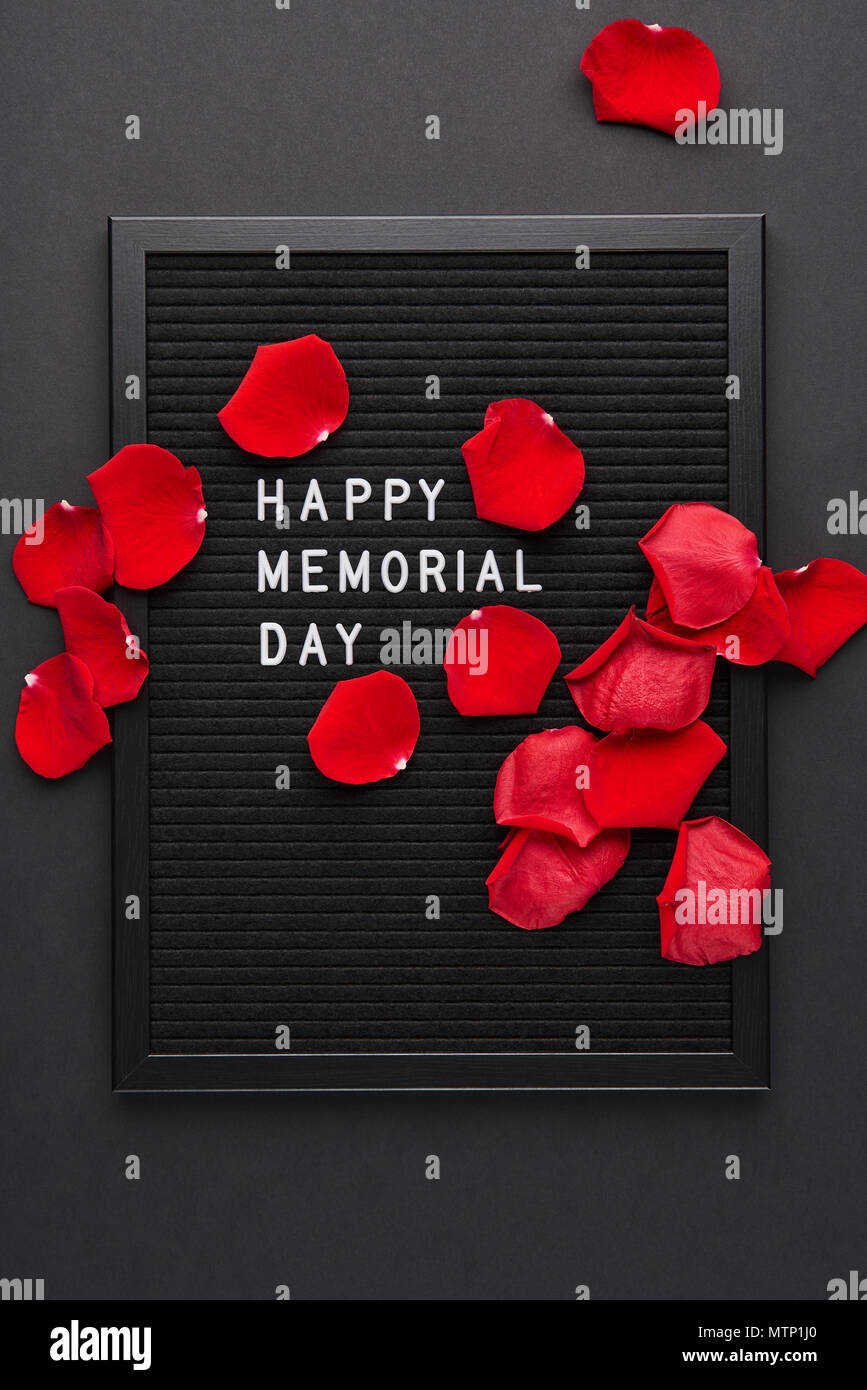 Letterboard nero bianco con lettere in plastica con citazione Happy Memorial Day e petali di rosa su sfondo nero. Foto Stock