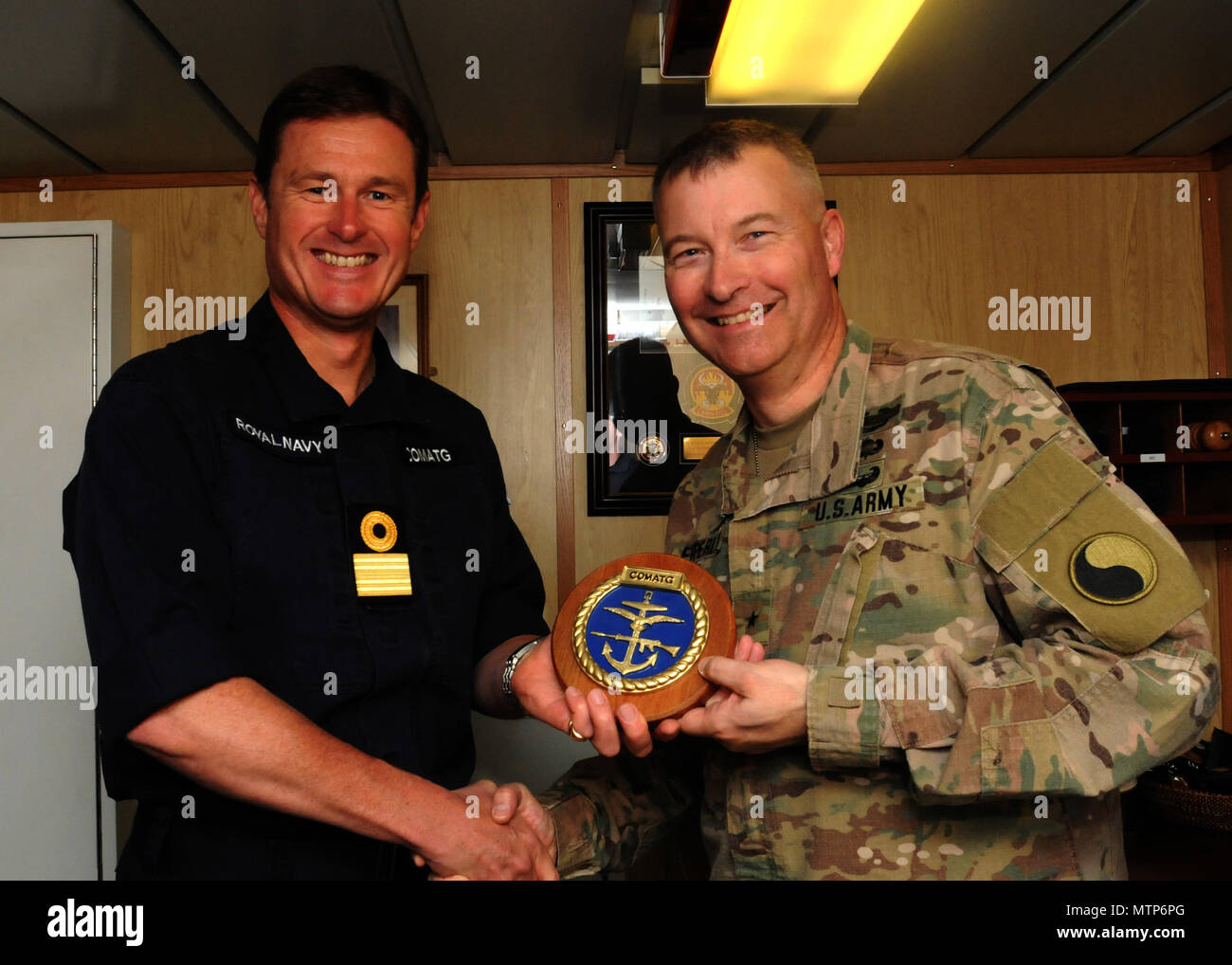 Commodore Andrew Burns, Commodore dell'HMS Ocean, presenta il Brigadiere Generale John Epperly, vice comandante generale per la ventinovesima divisione di fanteria, con una cresta COMATG sull'oceano HMS gennaio 11. La HMS Ocean è UK carrier in elicottero e l'ammiraglia della flotta della British Royal Navy (foto di U.S. Army Sgt. Kelly R. Gary, ventinovesima divisione di fanteria per Affari pubblici) Foto Stock