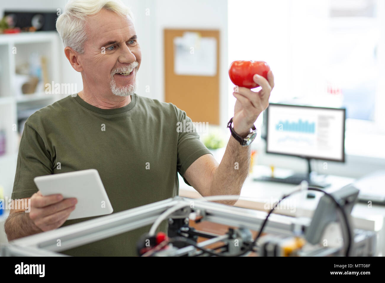 Allegro senior un uomo guarda il modello di pomodoro con sorriso Foto Stock