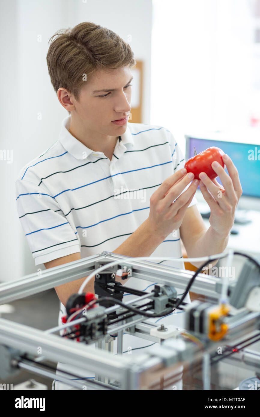 Piacevole giovane ingegnere scrutare rosso pomodoro stampato Foto Stock