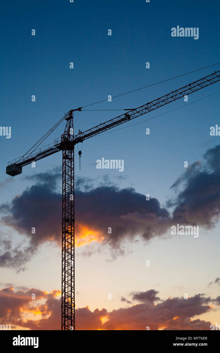 Sito in costruzione con gru silhouette al tramonto su blu cielo arancione Foto Stock