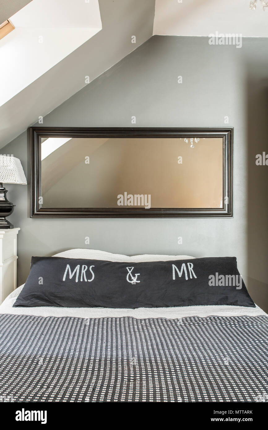 Nuova camera mansardata con specchio, grande letto, decorativo in bianco e nero la biancheria per il letto e i cuscini Foto Stock