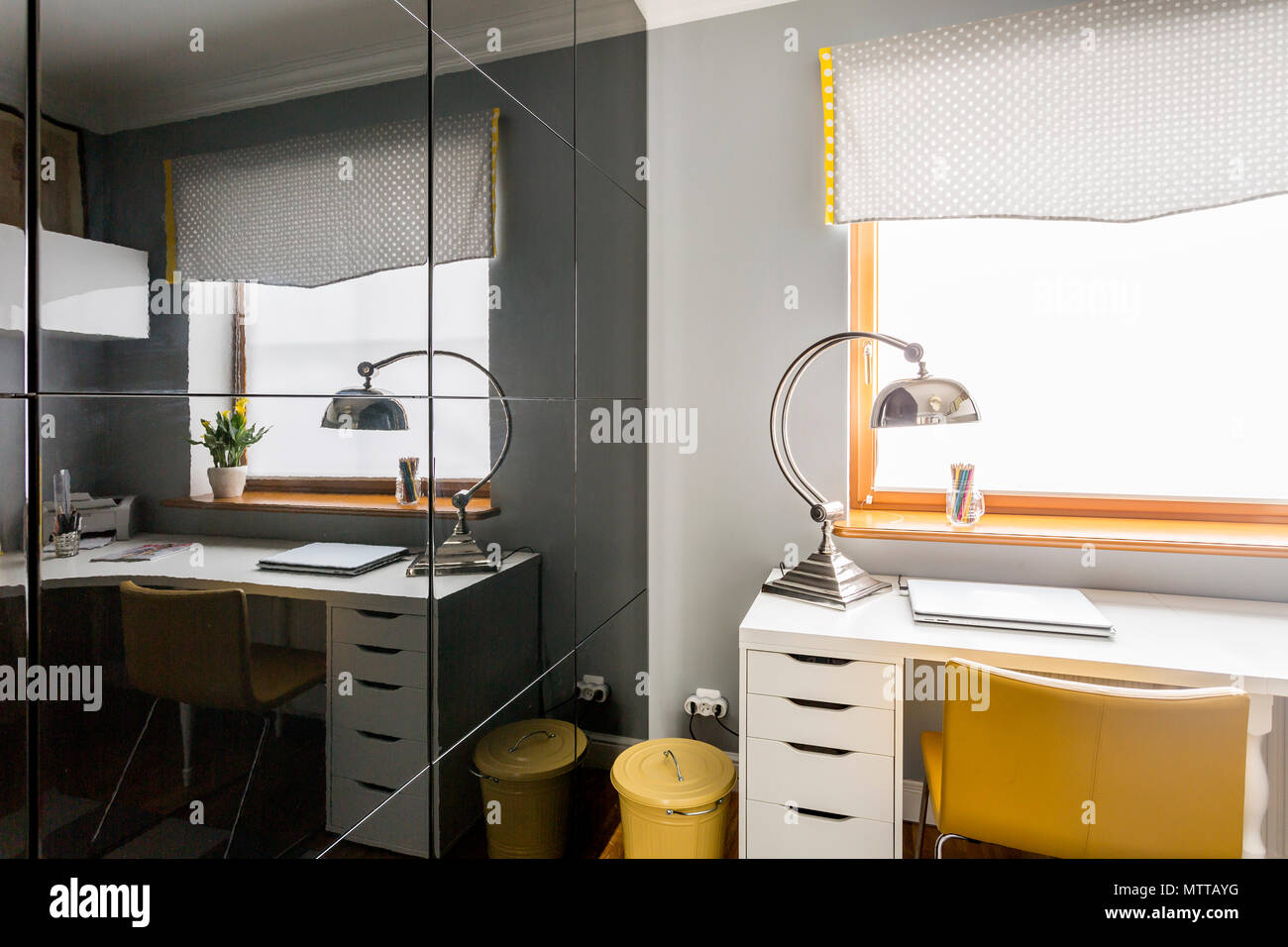 Elegante camera studio con vetro nero armadio scorrevole porte, scrivania bianco, giallo poltrona e lampada moderna Foto Stock
