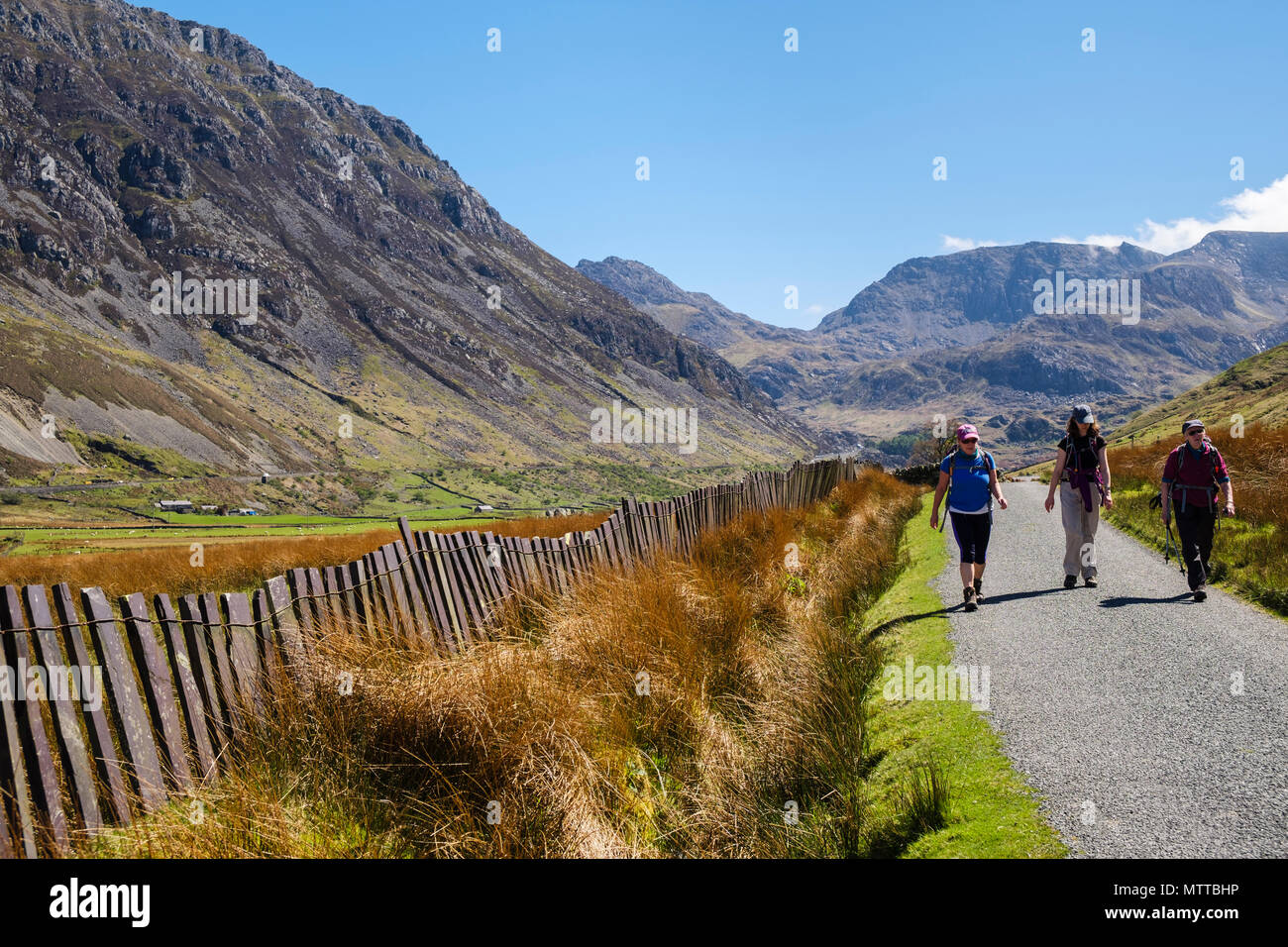 La gente che camminava su un vicolo del paese con tradizionale ardesia recinzione in Nant Ffrancon valley nel Parco Nazionale di Snowdonia in estate. Ogwen Gwynedd Wales UK Foto Stock