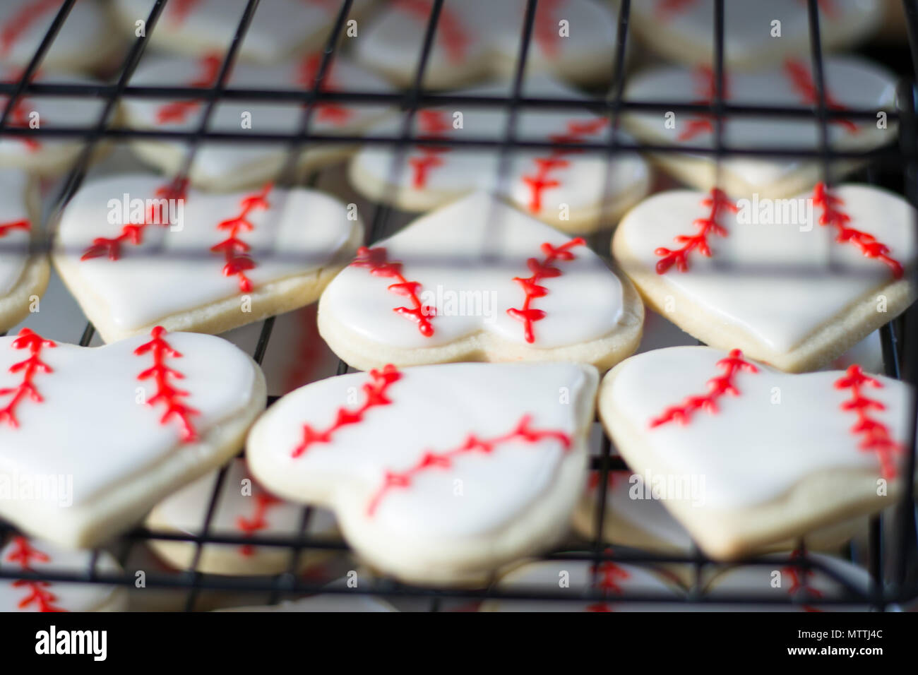 A forma di cuore di zucchero da baseball cookies il raffreddamento su scaffalature in pasticceria cucina Foto Stock