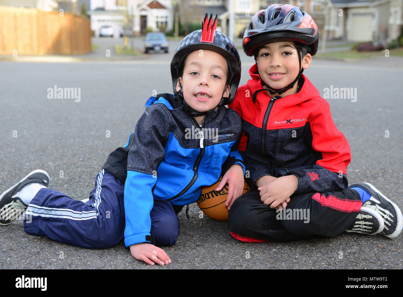 Due bambini giocano fuori casa loro a Bothell, Washington, sotto la cura di un capo della Guardia Costiera. Un bambino ha il citomegalovirus e l'altro ha l'ADHD. Le attività all'aperto e la supervisione promuovono lo sviluppo, il benessere e l'interazione con la famiglia. La madre bilancia le responsabilità come specialista delle operazioni nel 13° Distretto della Guardia Costiera, mantenendo la prontezza, i compiti di comunicazione e le capacità di risposta alle emergenze. Lo scenario dimostra il supporto della famiglia, la gestione del tempo e l'impegno nello sviluppo dei figli, pur adempiendo ai doveri operativi. Foto Stock