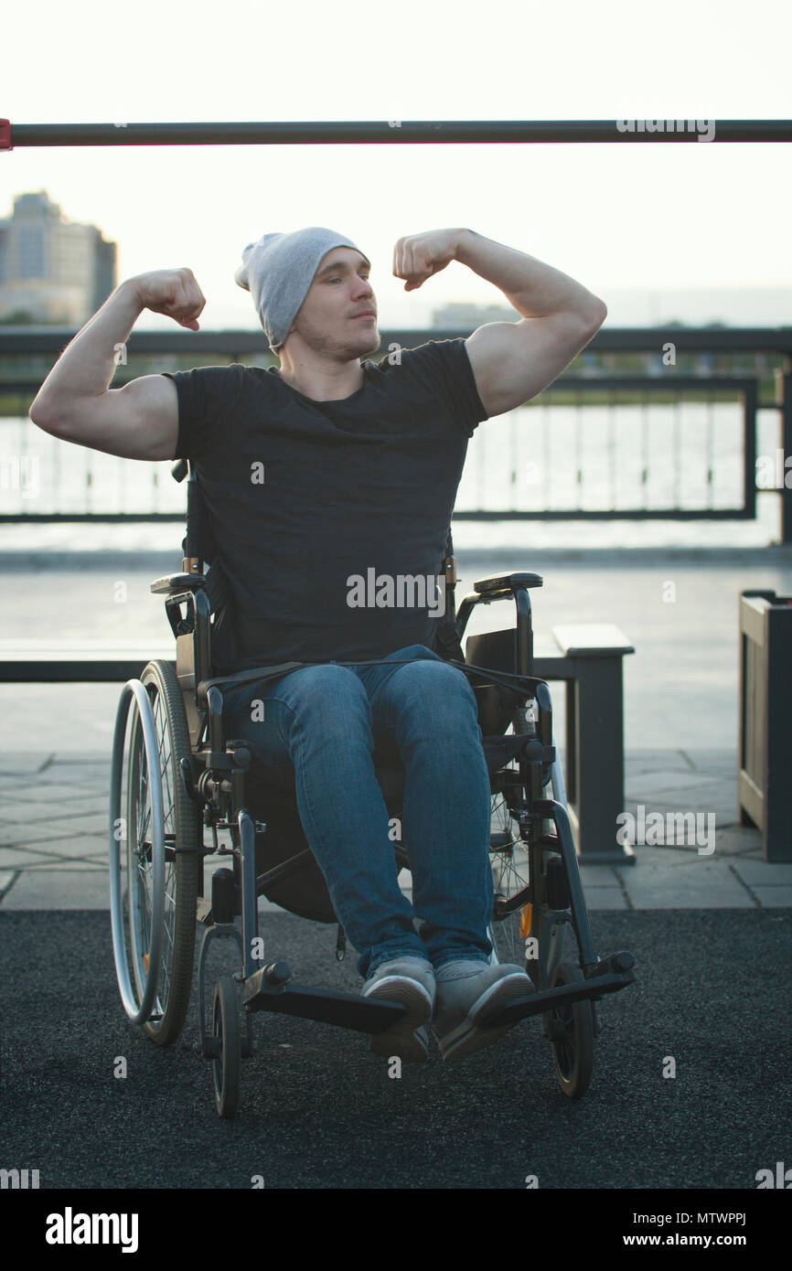 Muscolare uomo disabili in sedia a rotelle nella parte anteriore della traversa all'aperto Foto Stock