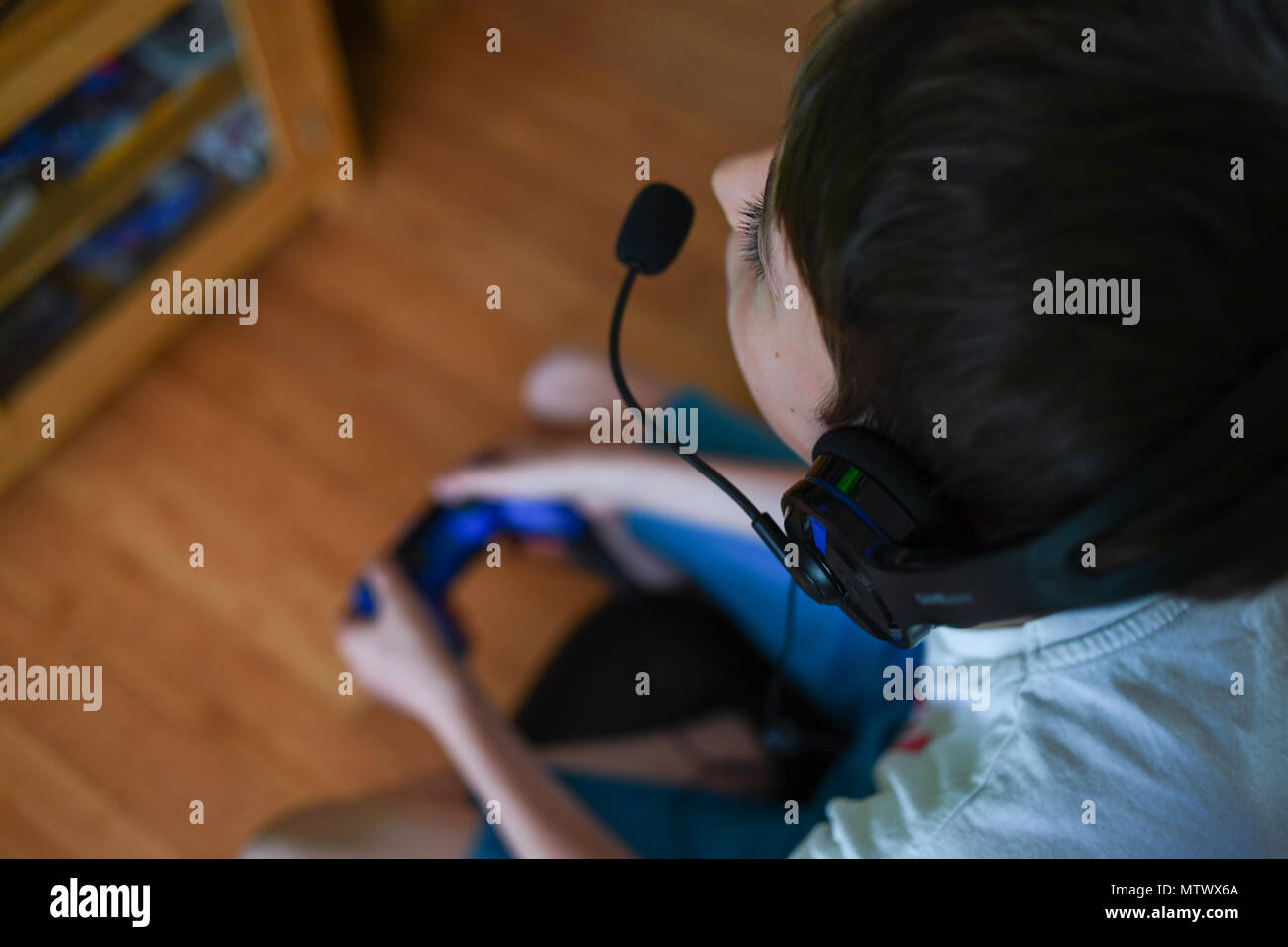 Un giovane ragazzo con una testa di gioco impostato e microfono sulla riproduzione su una playstation. Foto Stock