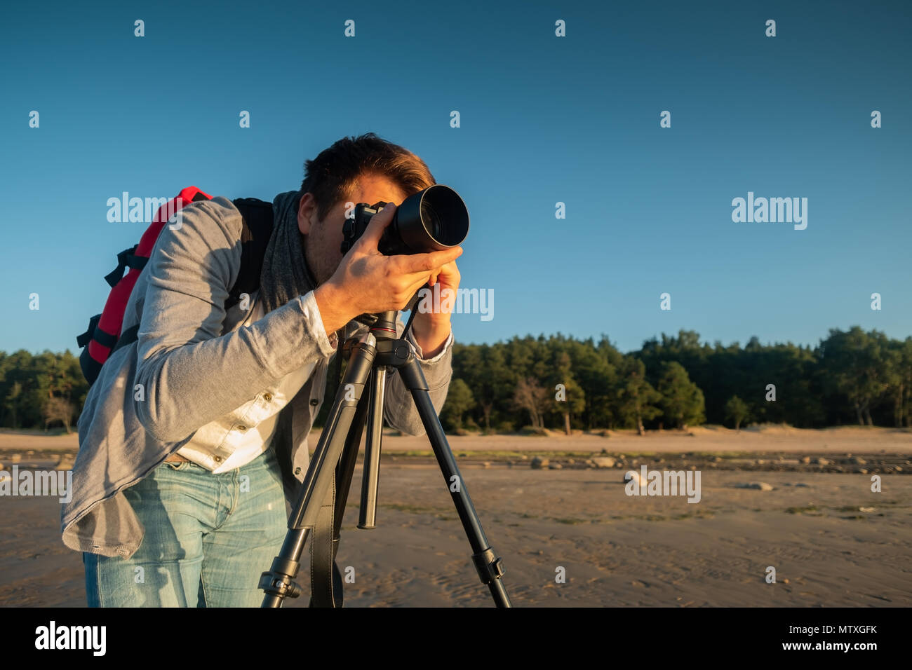 Fotografo professionista su posizione e rendere permanente la foto con il cavalletto sulla spiaggia Foto Stock