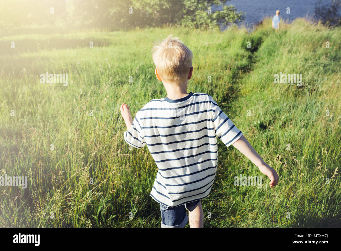 Ragazzo biondo correndo la distanza. Un bambino in natura. Realismo concettuale. Foto Stock