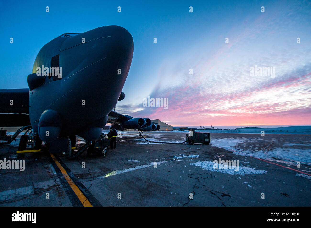Il sole sorge alle spalle di una B-52H Stratofortress a Minot Air Force Base, N.D., Gennaio 26, 2017. Avieri dal 5 Manutenzione aeromobili squadrone lavorare intorno all'orologio in tutte le condizioni atmosferiche per fornire B-52 firepower on demand. (U.S. Air Force foto/Senior Airman J.T. Armstrong) Foto Stock