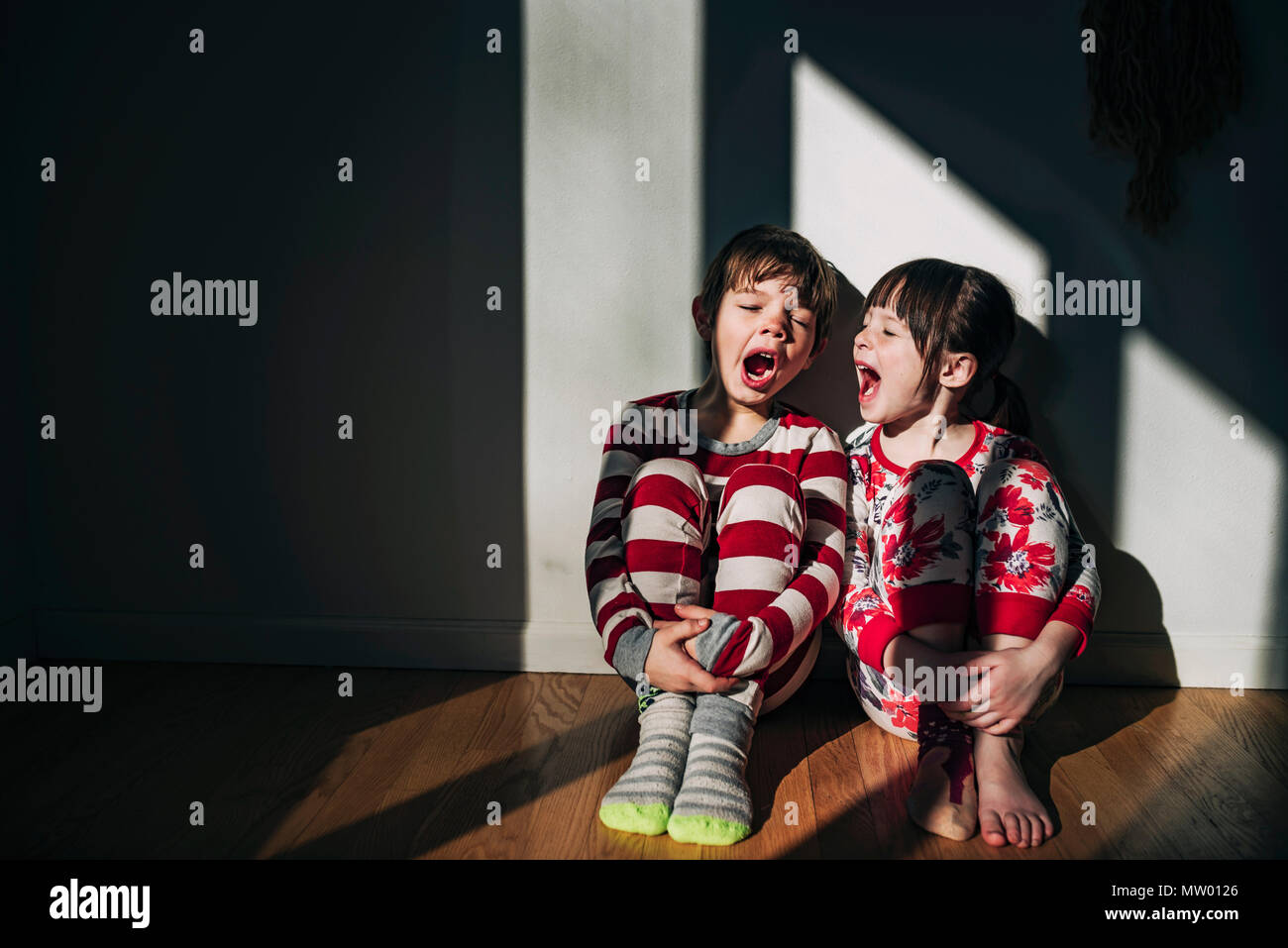 Un ragazzo e una ragazza seduta sul pavimento sbadigli Foto Stock