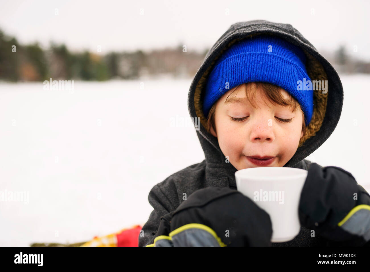 Ragazzo in piedi nella neve bere cioccolata calda Foto Stock