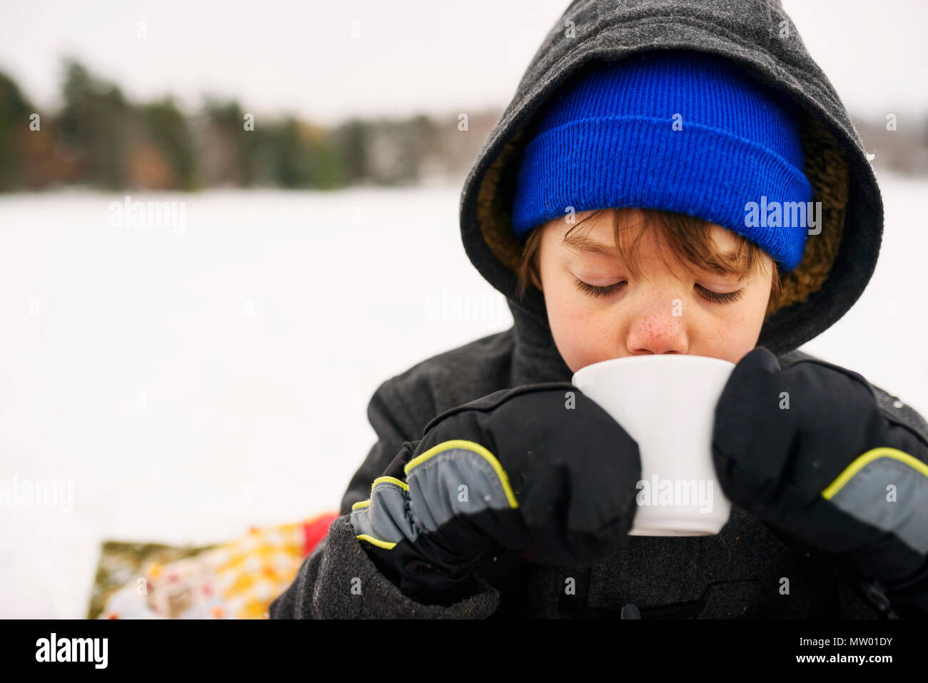 Ragazzo in piedi nella neve bere cioccolata calda Foto Stock