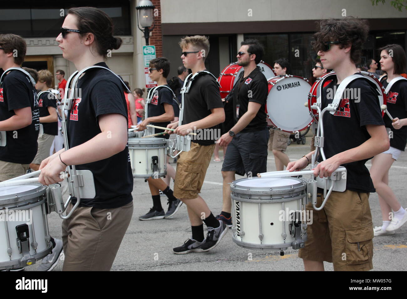 Il Memorial Day Parade high school band drum sezione marciando attraverso il calore. Foto Stock