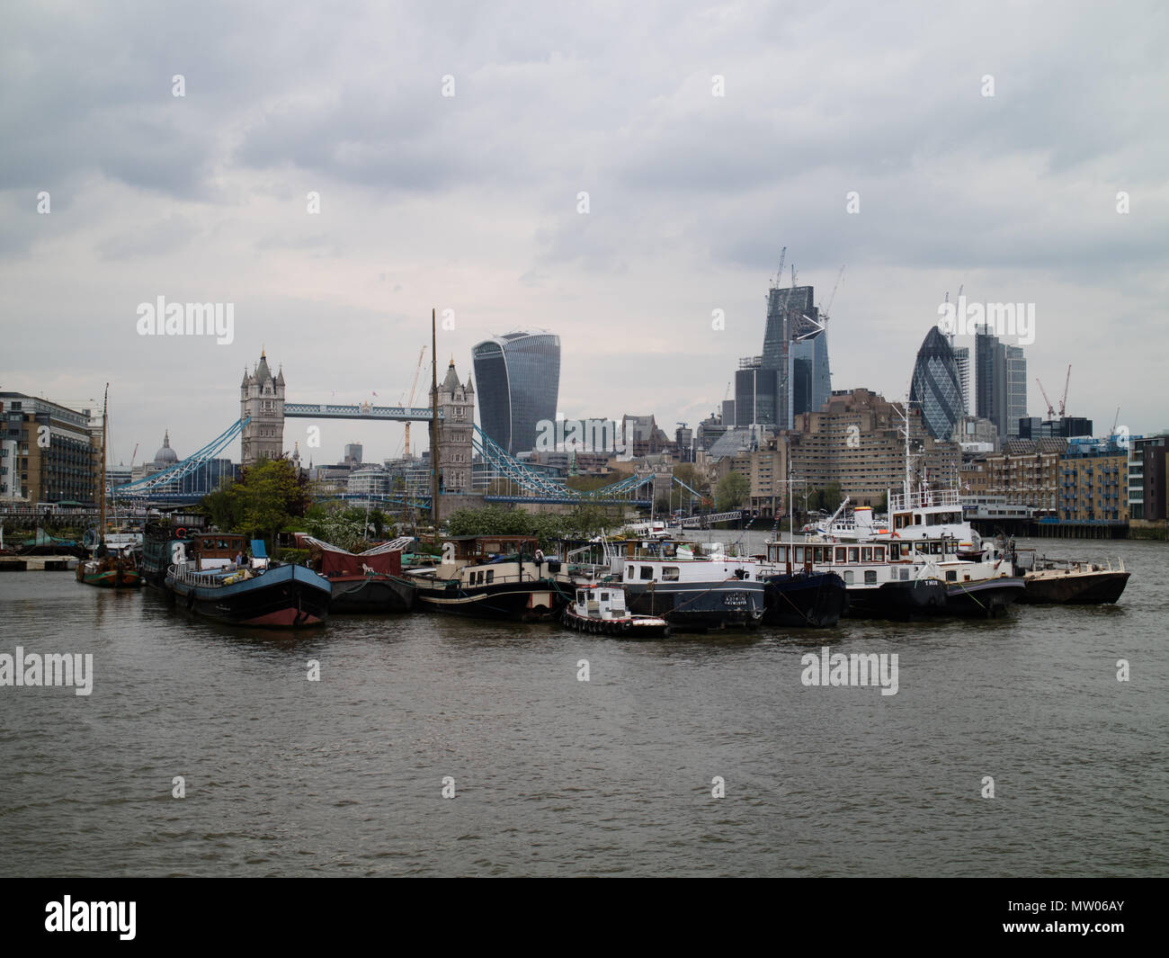 Vista del paesaggio a est del Tower Bridge di Londra con un gruppo di barche chiatta a metà del primo piano. Spazio di copia di sommità e di fondo Foto Stock
