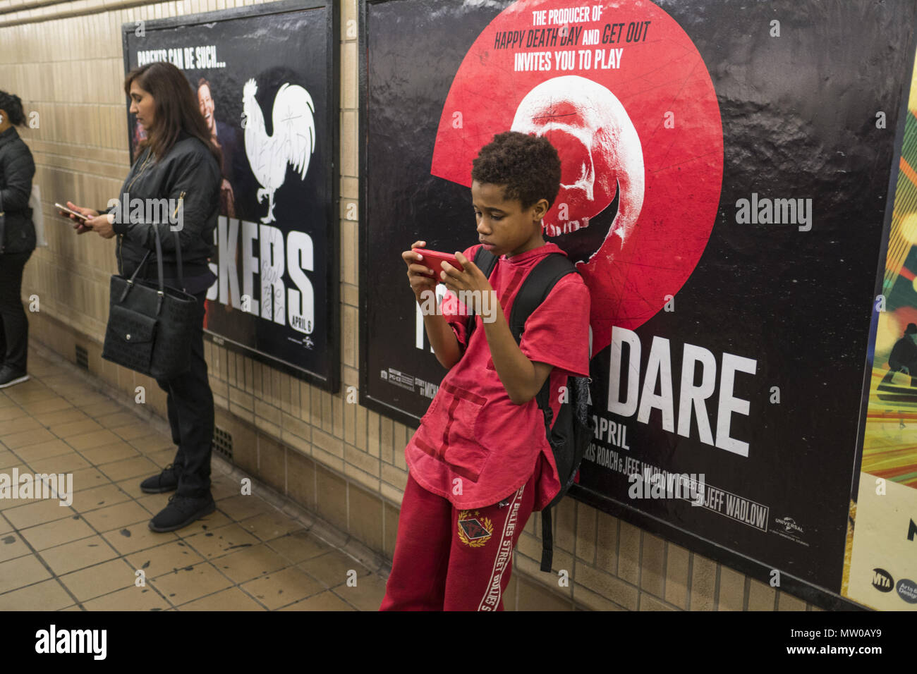 Ragazzo e ragazza di utilizzare i loro telefoni cellulari in attesa per un'uptown 6 treno alla cinquantunesima sulla Lexington Avenue linea in midtown Manhattan. Foto Stock