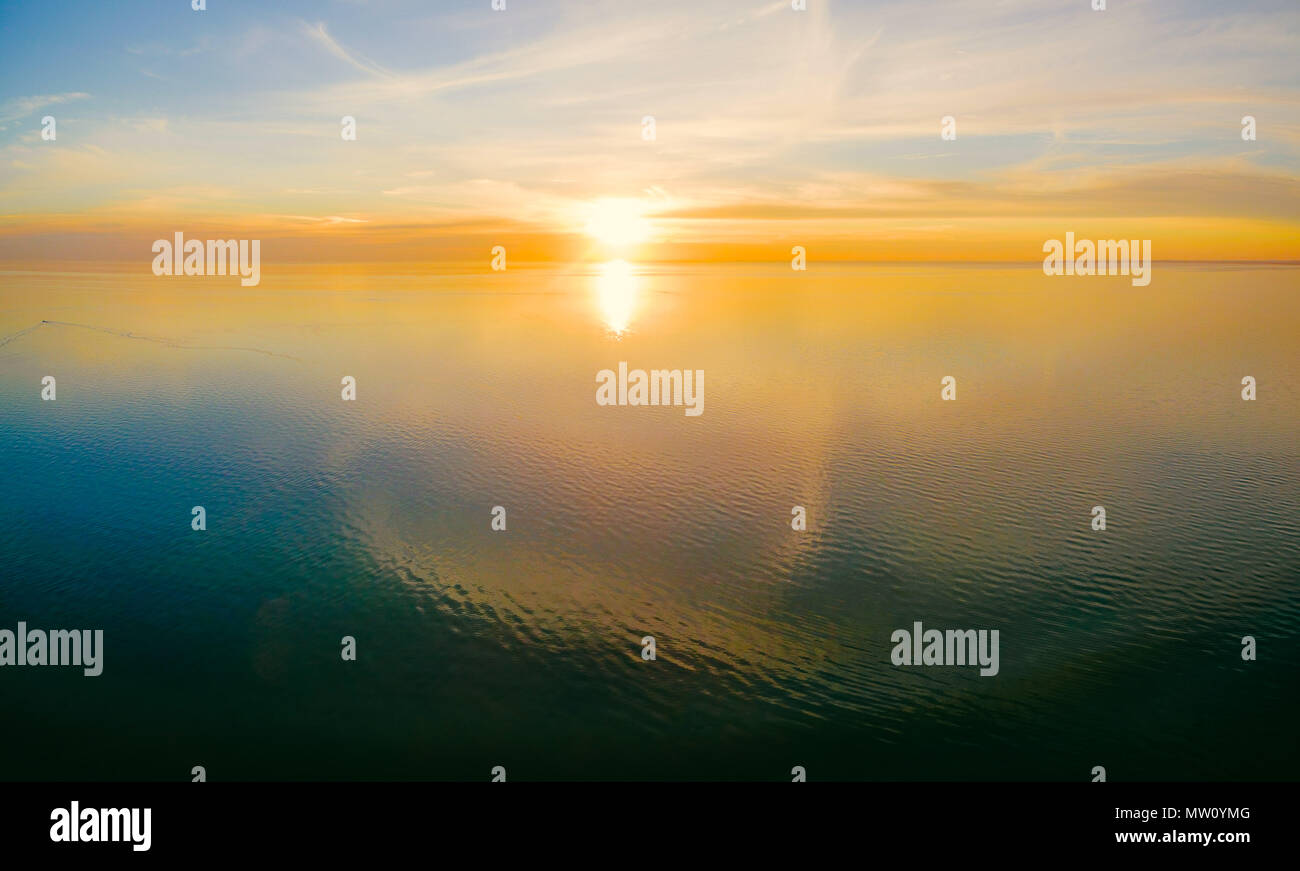 Panoramica aerea seascape - tramonto su acque calme con cloud riflessioni e bellissimi colori luminosi Foto Stock