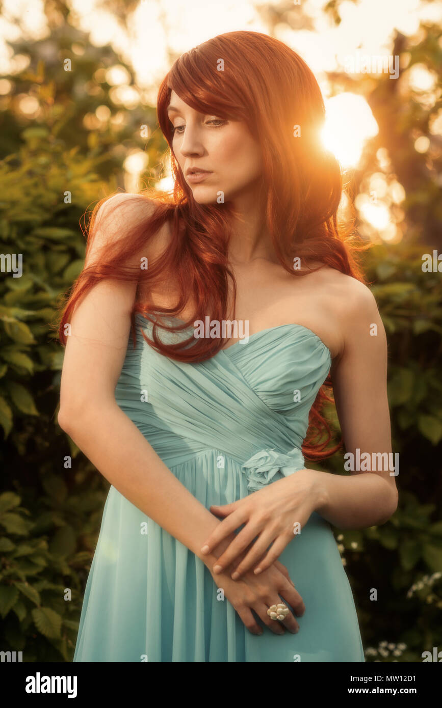 Donna con lunghi capelli rossi in primavera sbocciano i fiori in tarda serata sole Foto Stock