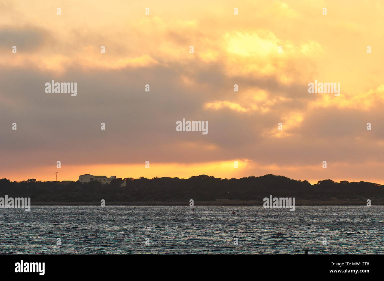 Tramonto Dorato da Sa Boca con Can Marroig proprietà backlighted in background nel Parco Naturale di Ses Salines (Formentera, isole Baleari, Spagna) Foto Stock