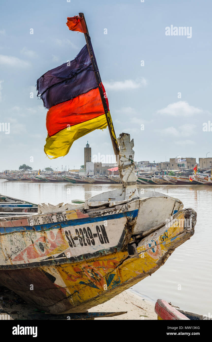 St Louis, Senegal - 12 Ottobre 2014: i colori di legno verniciato la pesca in barca o in piroga con bandiera tedesca a costa. Foto Stock