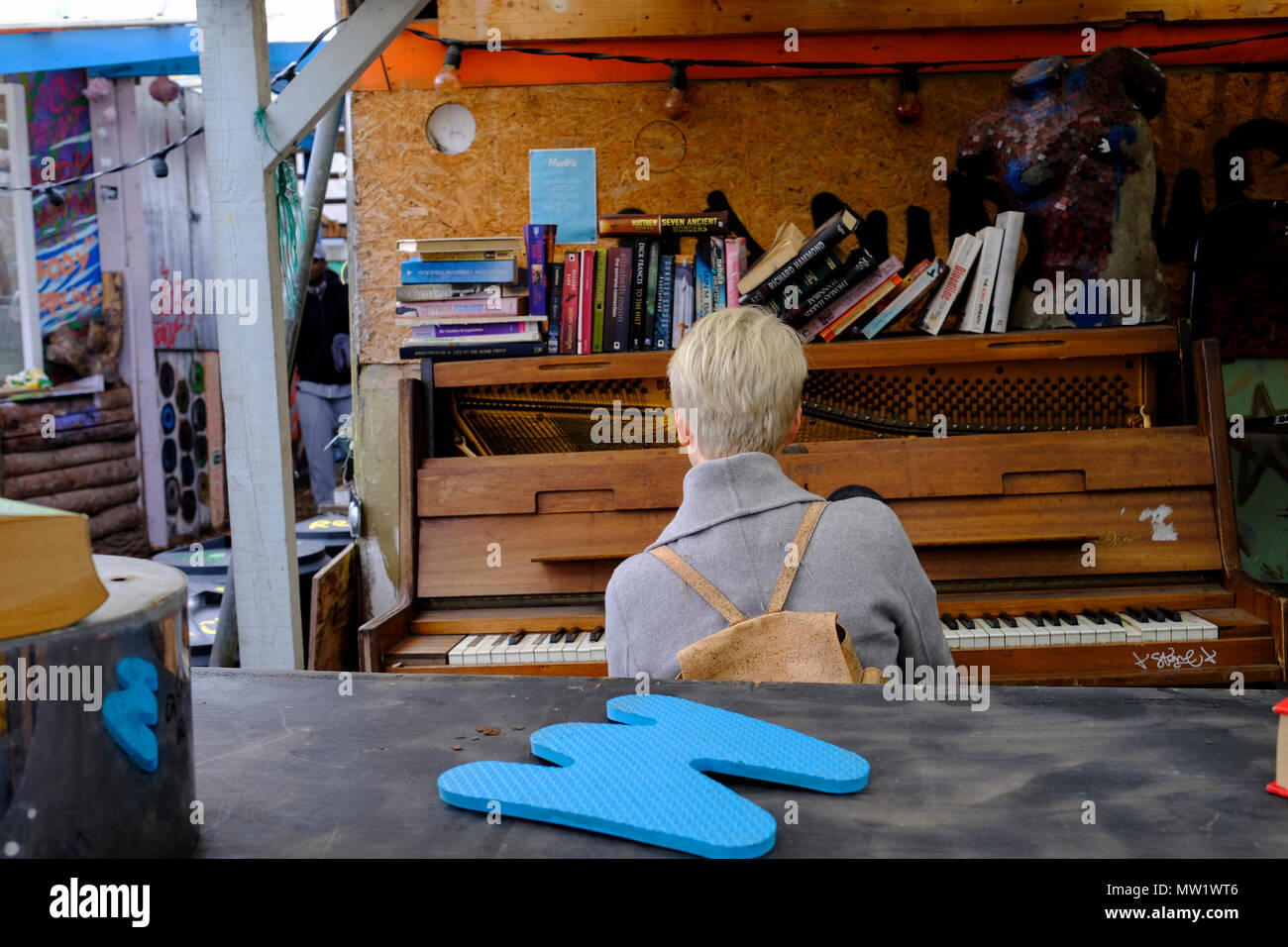 Una donna è suonare il pianoforte presso la comunità di nomadi giardino off Brick Lane in Shoreditch, East London, England, Regno Unito. Foto Stock