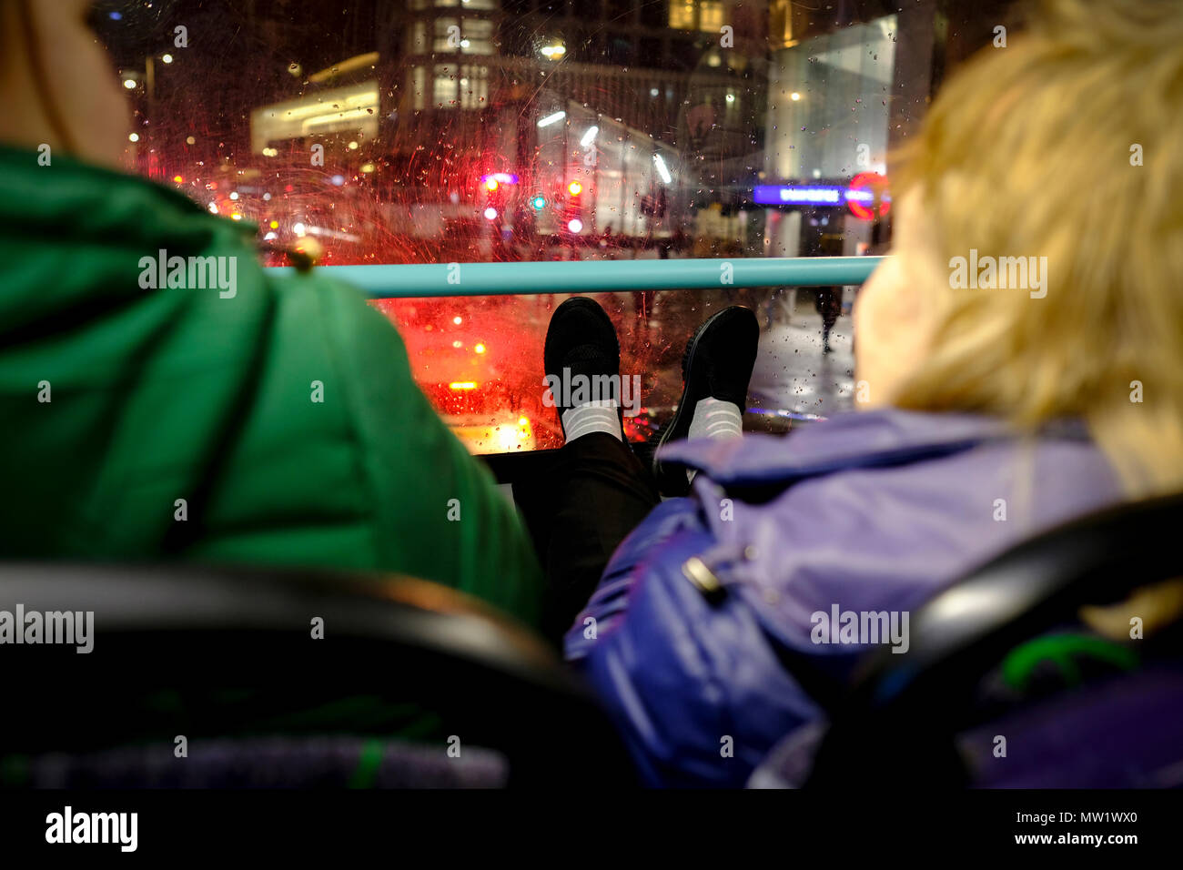 Donne appoggiando i piedi sulla parte anteriore della finestra del davanzale del double decker bus in Londra, Regno Unito. Foto Stock