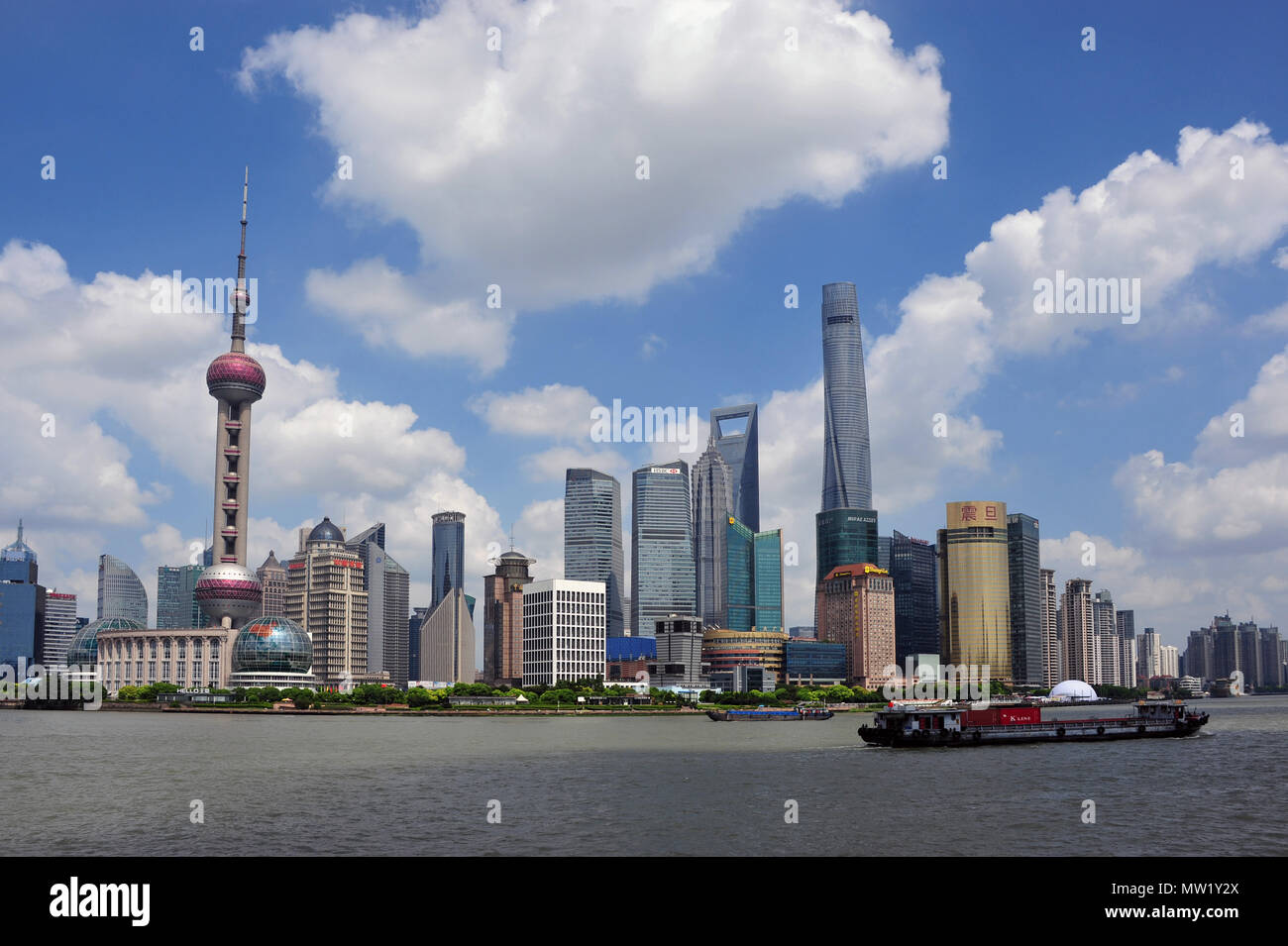 Vista panoramica sullo skyline di Pudong oltre il Fiume Huangpu con chiatte e cloudscape, Shanghai, Cina Foto Stock