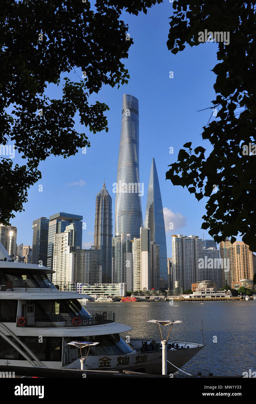 Lo skyline di Pudong oltre il Fiume Huangpu incorniciato da alberi con la barca in primo piano che mostra alcuni degli edifici più alti del mondo, Shanghai, Cina Foto Stock