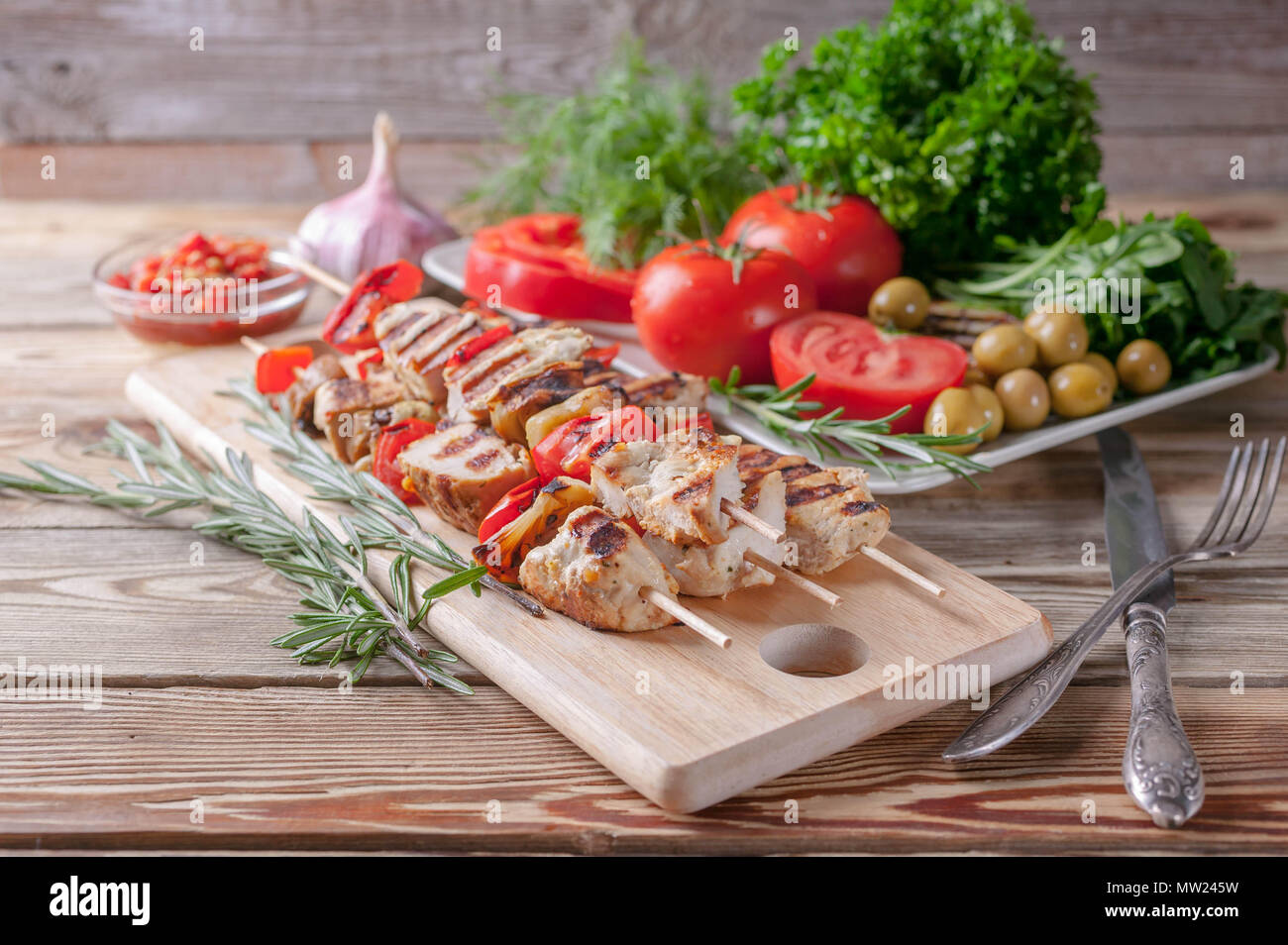 Spiedini di pollo. La verdura fresca e erbe aromatiche. Pomodori rossi, rosso peperoni, prezzemolo, aneto, rucola, aglio e rosmarino. Foto Stock