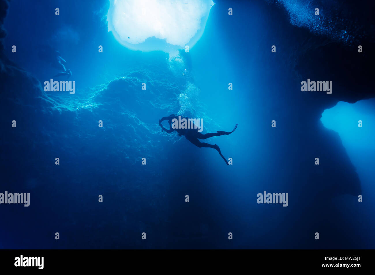 Vista verso l'alto del subacqueo nuoto più in profondità dentro un buco blu sotto il bordo del atollo corallino nel Pacifico del sud Foto Stock