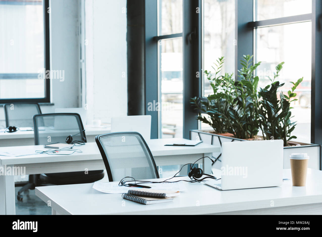 Auricolari e computer portatili su tavole in un ufficio moderno Foto Stock