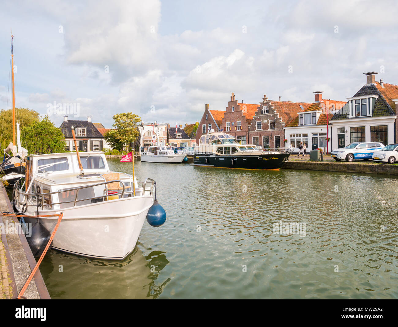 Porto con barche e quayside con case storiche nella città vecchia di Makkum, Friesland, Paesi Bassi Foto Stock