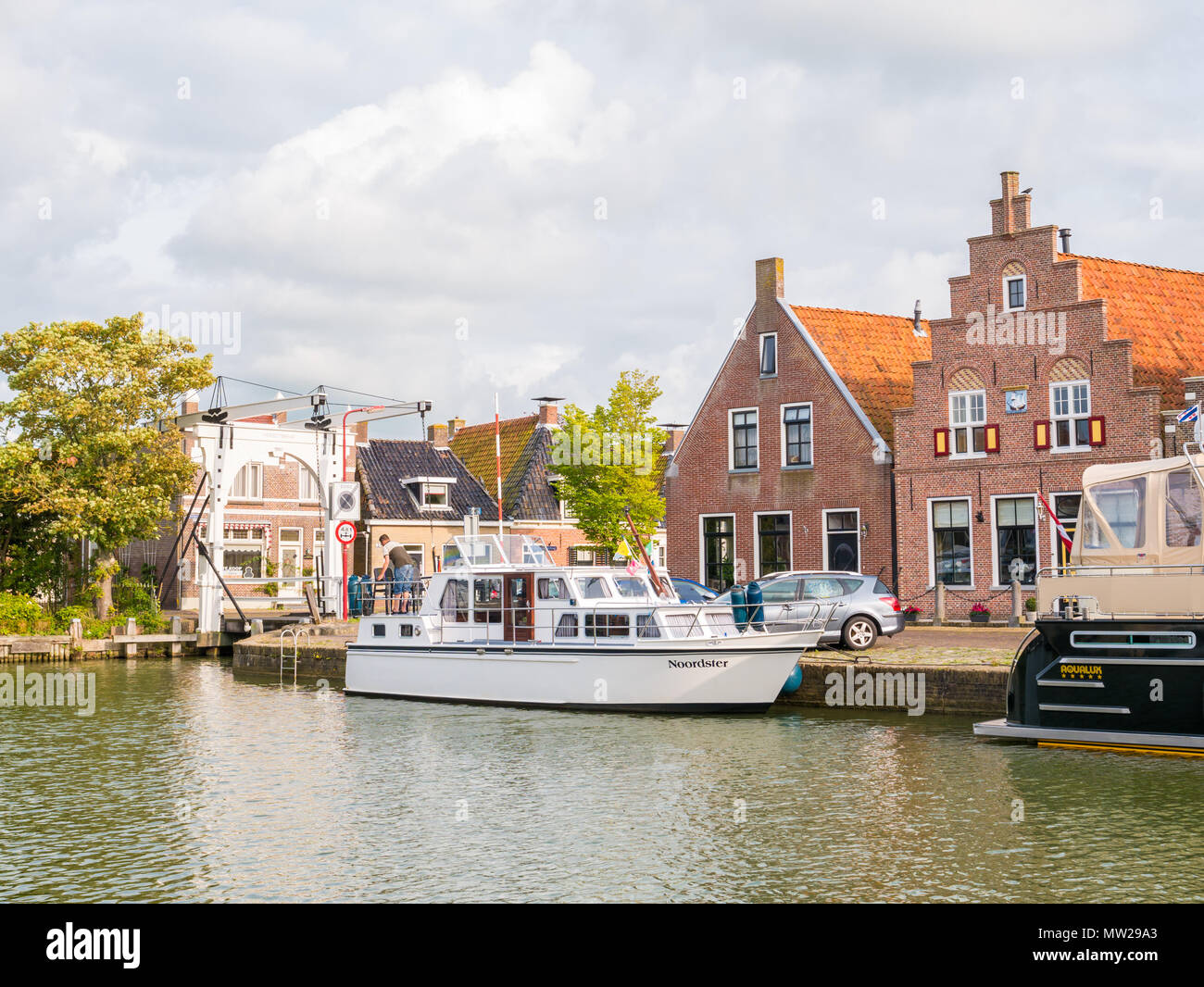 Barca in porto, ponte levatoio e case storiche nella città vecchia di Makkum, Friesland, Paesi Bassi Foto Stock