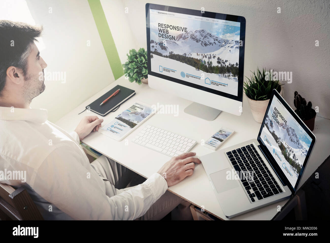 Uomo che lavora con i dispositivi con sito reattivo. Tutti i grafici dello schermo sono costituiti. Foto Stock