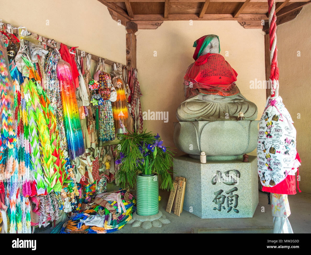 Statua buddista, senbazuru origami offerte di gru, bell corda con minnie mouse bib, Negoroji, tempio 82, Shikoku 88 tempio pellegrinaggio, , Giappone Foto Stock