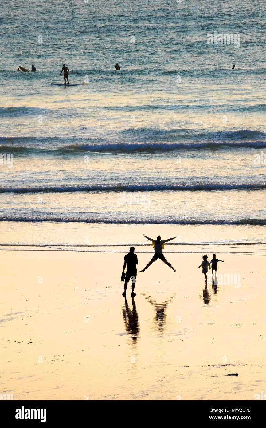Una famiglia di vacanzieri stagliano al tramonto di sera su Fistral Beach in Newquay in Cornovaglia. Foto Stock