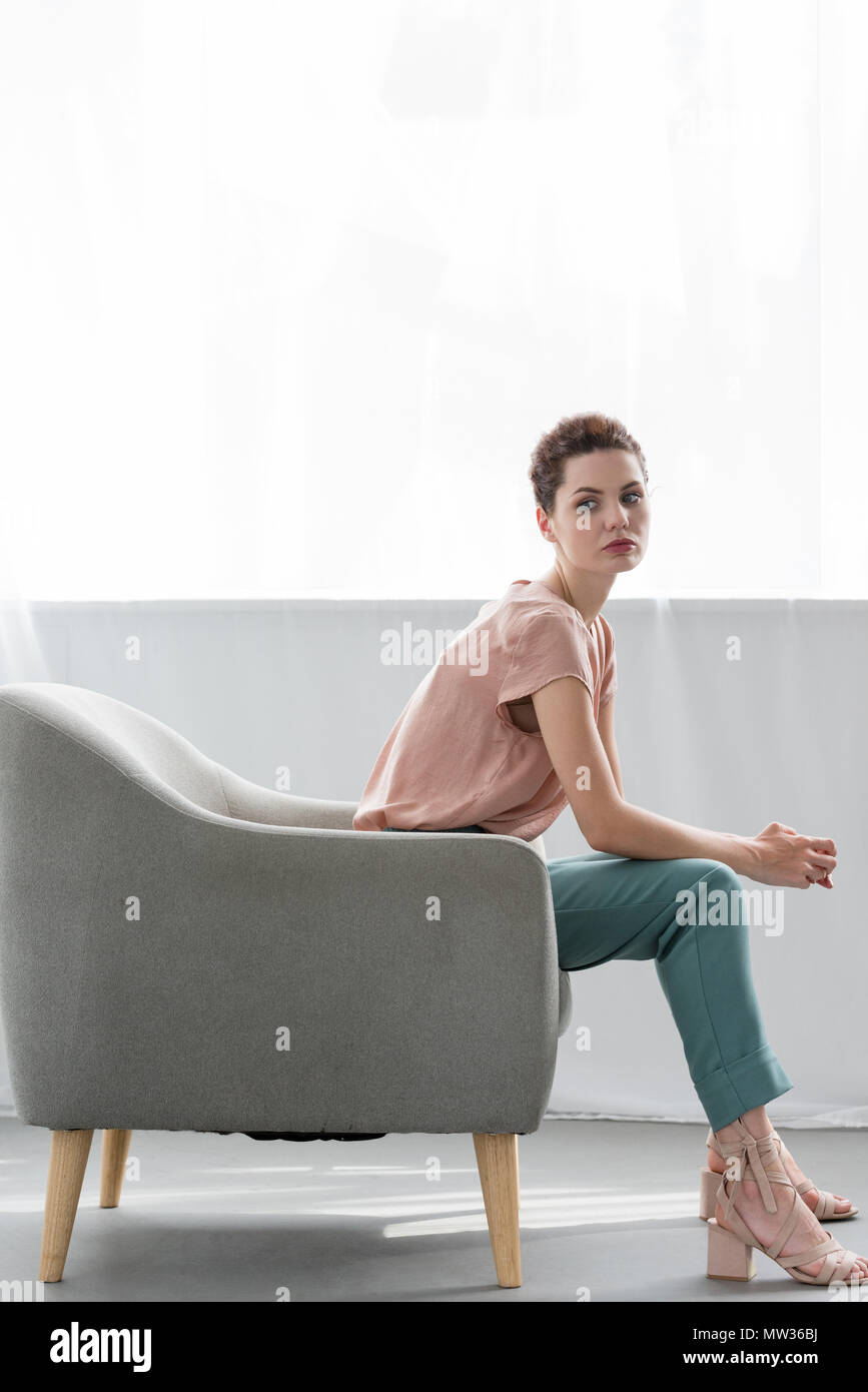 Vista laterale di attraente giovane donna seduta sulla poltrona di casa  Foto stock - Alamy